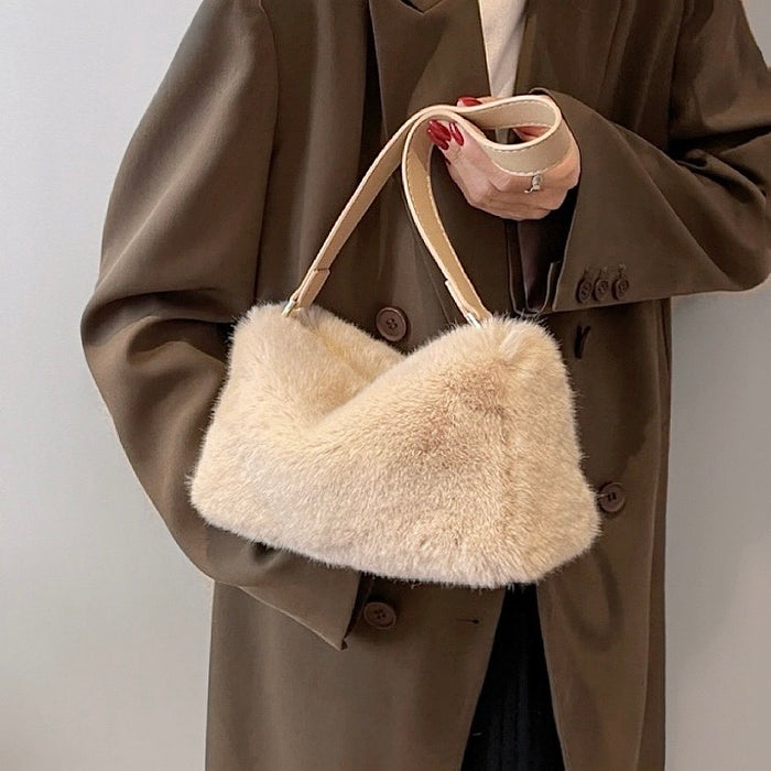 Model carrying a beige mini fluffy shearling baguette bag handheld, great for daily carry and travel.
