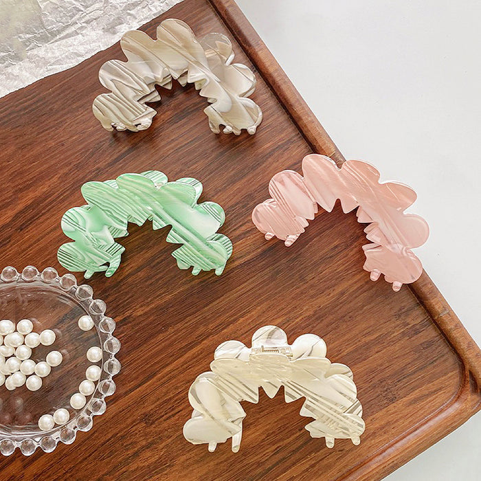 Four Acrylic moon hair claws in white, green, pink, and cream with wavy, scalloped edges.