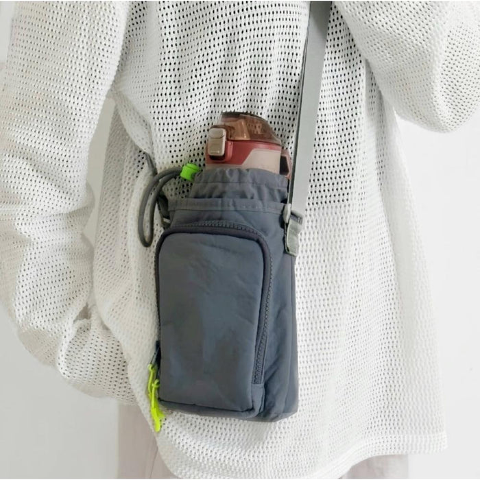 A model wearing a grey crossbody bottle bag, showcasing its compact and lightweight urban utility style.