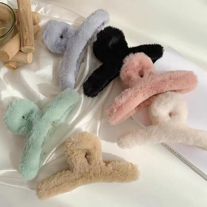 Six plush hair claws in pastel pink, mint, beige, white, black, and grey on a white surface.