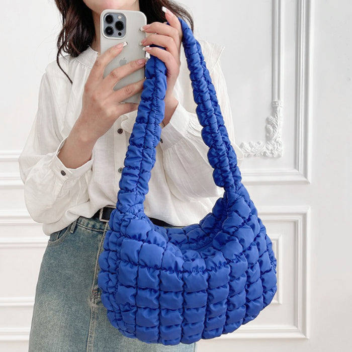 Model holding the blue puffy shoulder bag, showcasing the quilted puffy fabric.