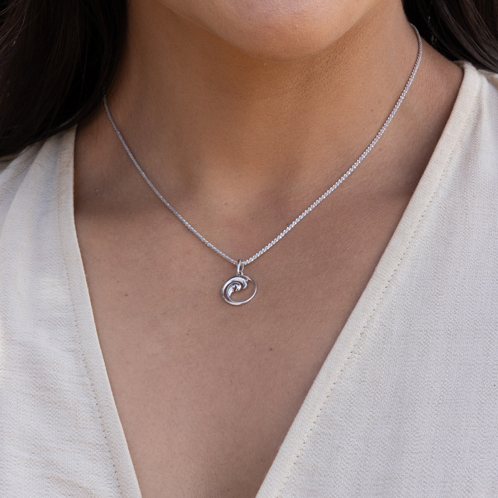 Close up of Nalu Pendant / Charm in Sterling Silver on a woman's neckline
