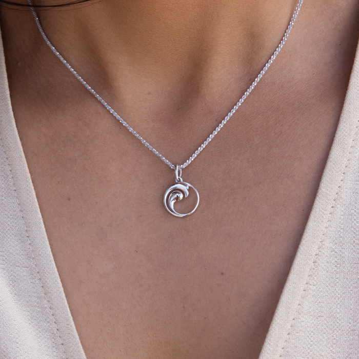 Close up of Nalu Pendant / Charm in Sterling Silver on a woman's neckline