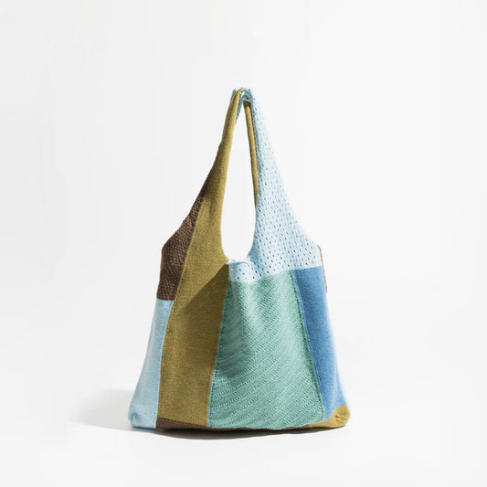 Front view of the slouchy color-block crochet tote bag featuring panels of muted blue, sage green, and earthy brown knit fabric.