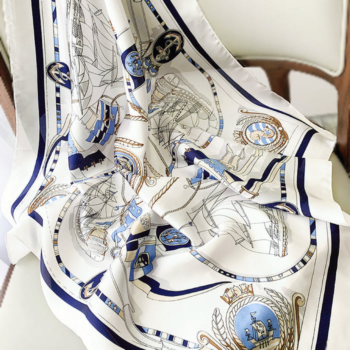 Flat lay of a White satin square scarf with blue nautical chart design, ships, and anchors in navy.