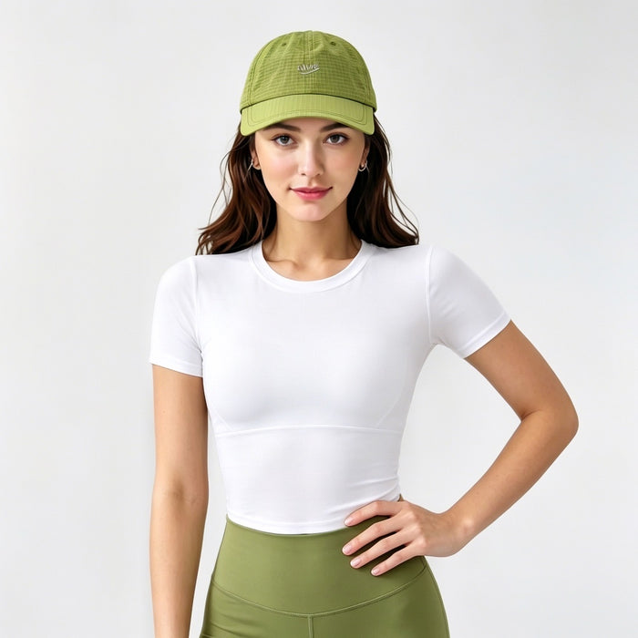 Model styling a bright green quick dry cap for a functional gorpcore outfit with an athletic top.