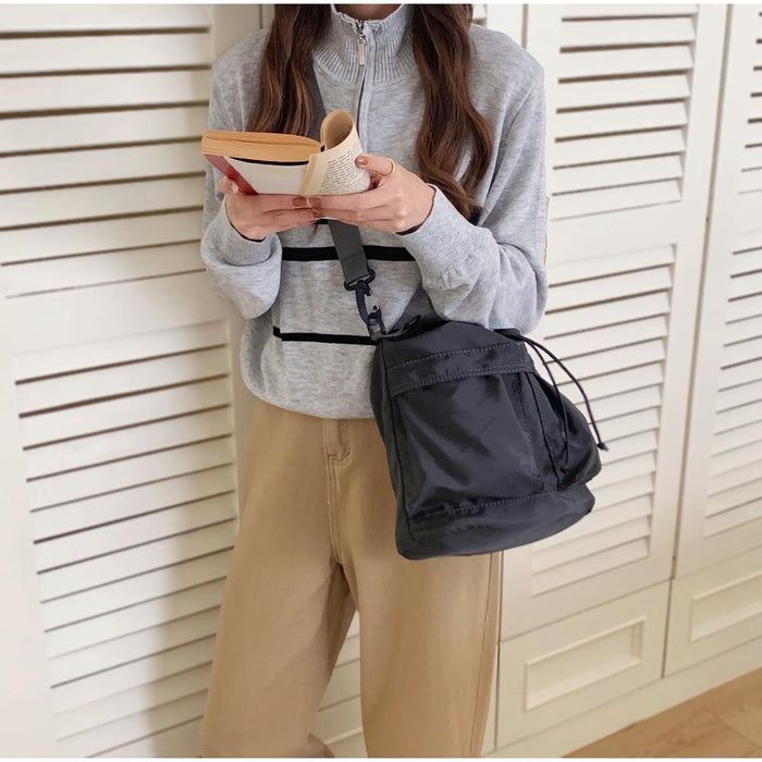 Front view of a model carrying the black nylon bag crossbody style.