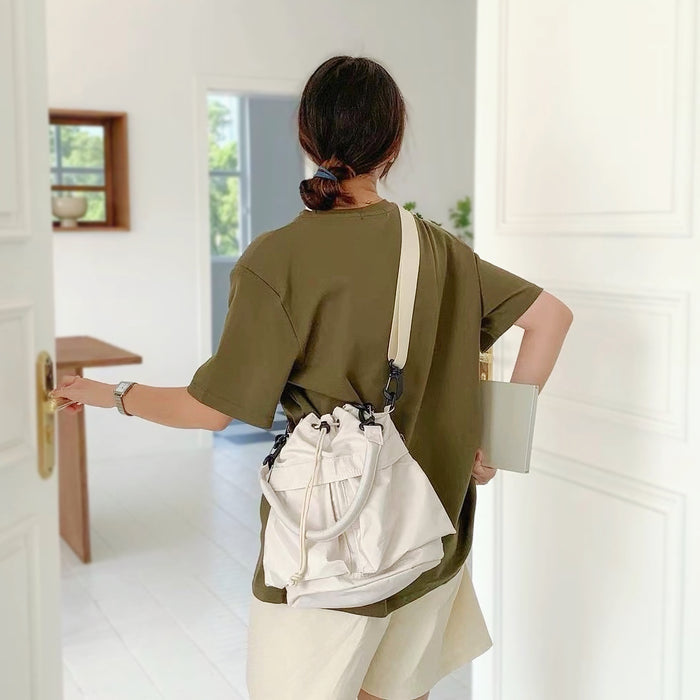 Back view of the white nylon bucket bag being worn by a model.