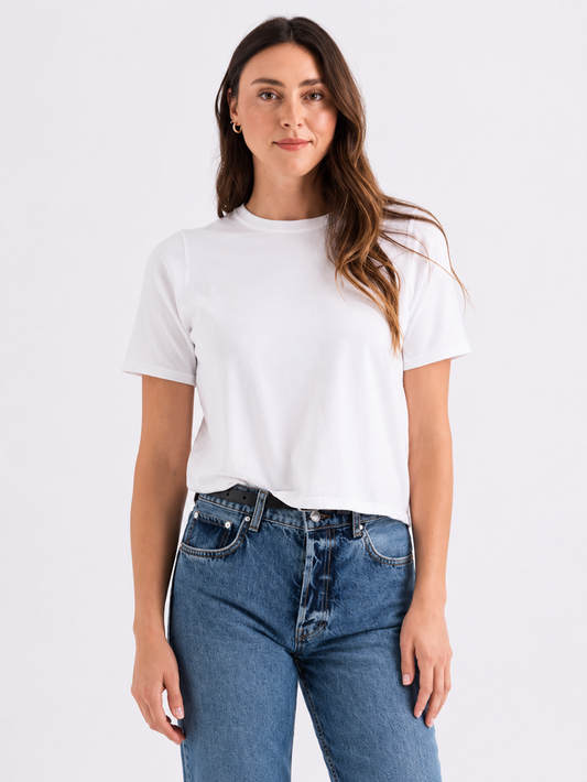 Woman wearing a white t-shirt and blue jeans on a plain background