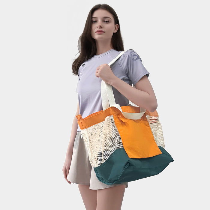 Model carrying the orange and green reversible tote bag by its shoulder straps.