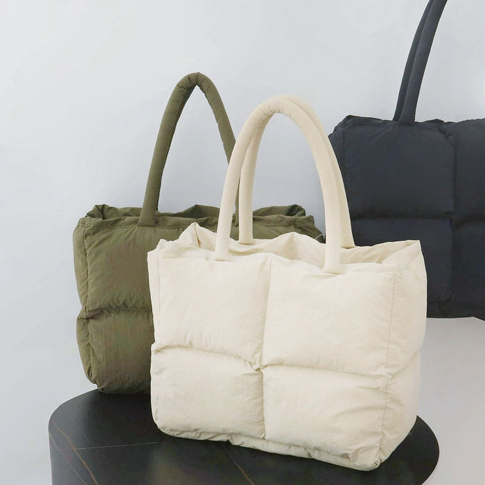 Three padded nylon tote bags in olive green, cream, white and black, showcasing their soft, quilted design.