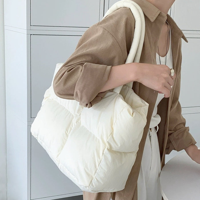 Model wearing the cream white padded tote bag on her shoulder over a brown shirt.