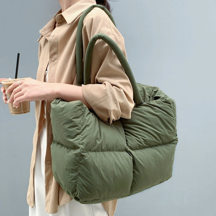 Side view of model carrying the olive green padded tote bag on her shoulder.