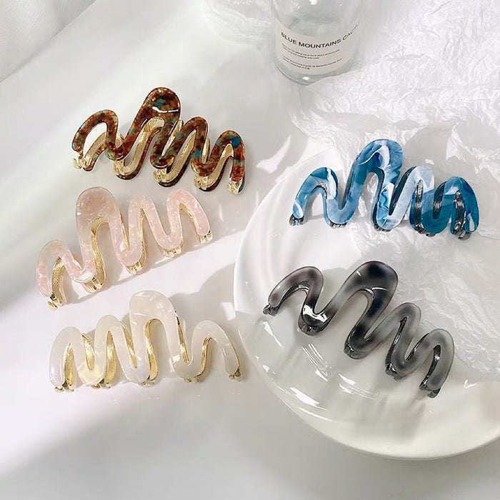 Front view of Four painted wave hair claws in brown, blue, pink, white, and black.