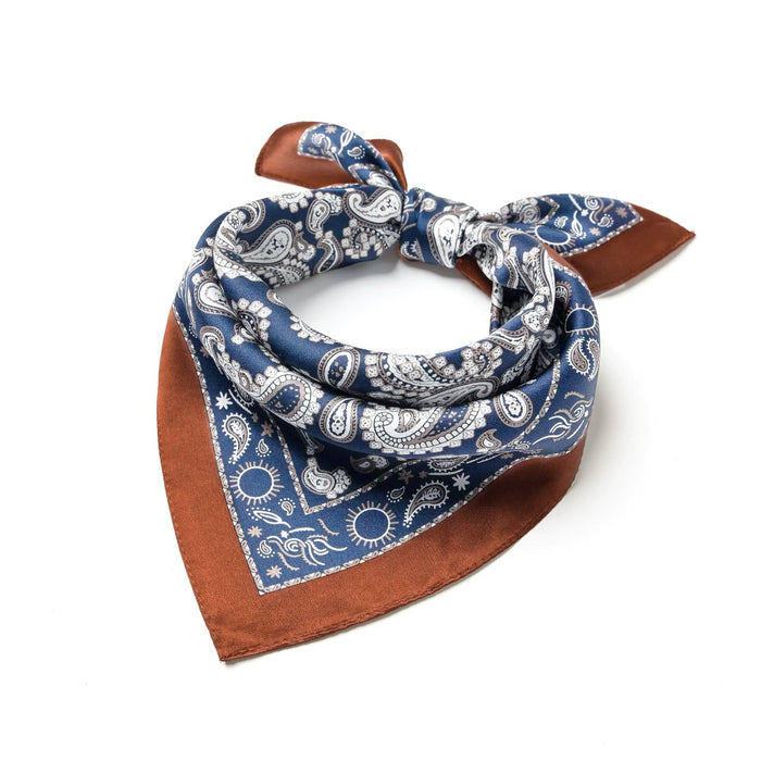 Folded blue paisley scarf highlighting intricate traditional pattern and soft silk-blend texture for luxurious travel.