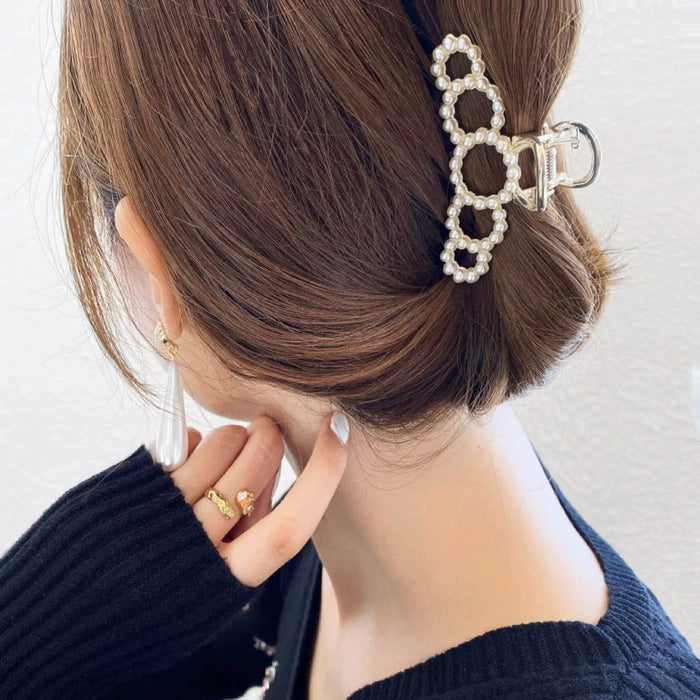 Side view of model styling a medium pearl clip; professional office chic hair accessory for daily use.
