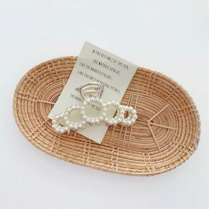 Fan-shaped pearl hair claw on a tray; elegant budget-friendly wedding guest hair accessory.