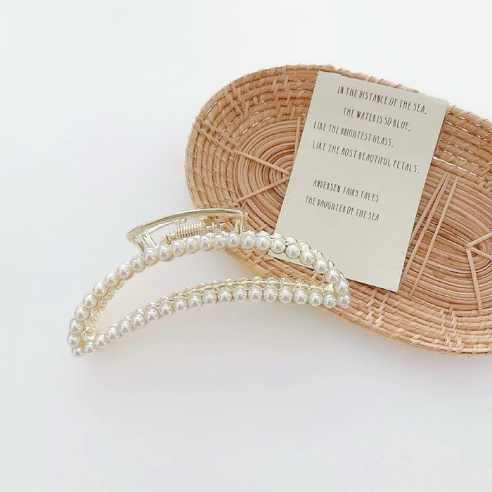 Detail of the curved metal claw with small pearls; showcasing the anti-tarnish finish.