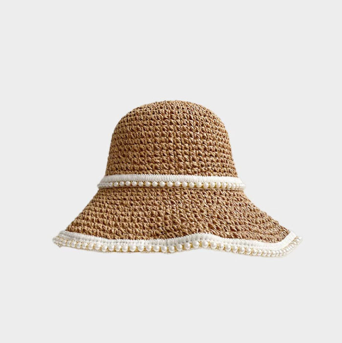 Front view of khaki straw hat and shimmering pearl band presenting elegant coastal accessory.