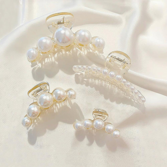 Four sizes of pearl reverie hair claws in a flat lay; elegant ABS hair accessories for long thick hair.
