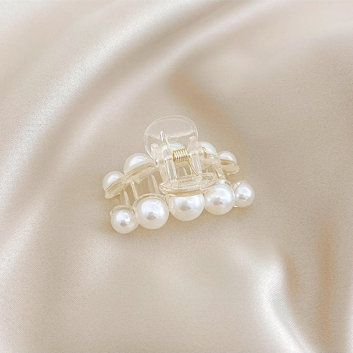 Close-up of a horizontal pearl hair clip; showing the high-tension grip and embedded pearl design.
