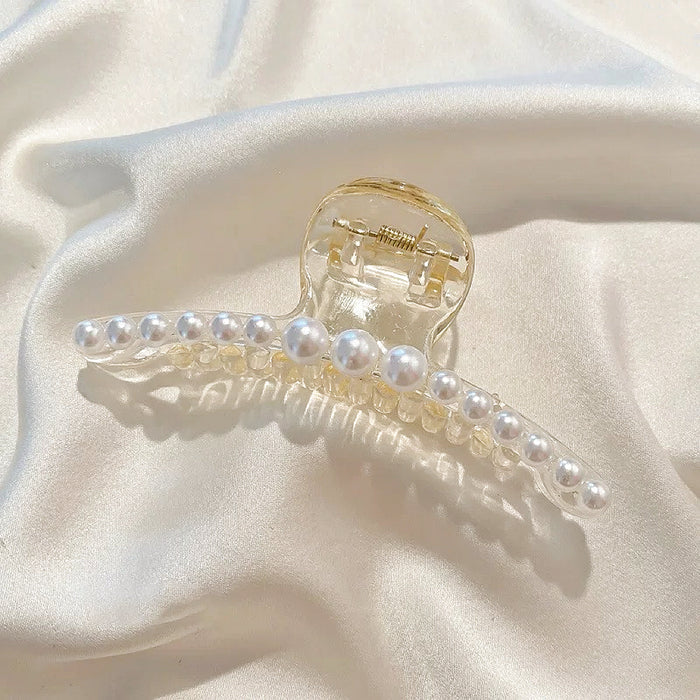 Minimalist view of a pearl hair claw on a cream fabric; best affordable hair accessory under $20.