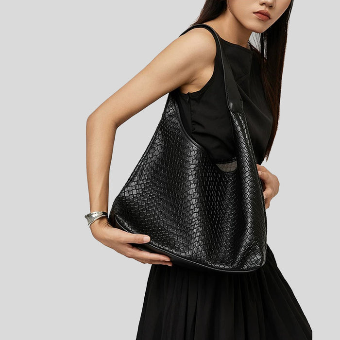 Model styling the black pebble texture shoulder bag with a black dress.