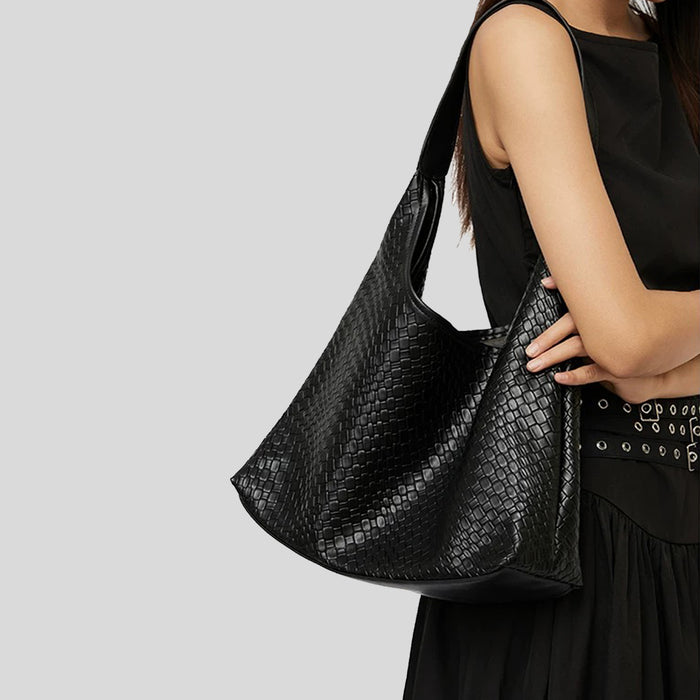 Side view of the black pebble leather bag being worn on the shoulder.