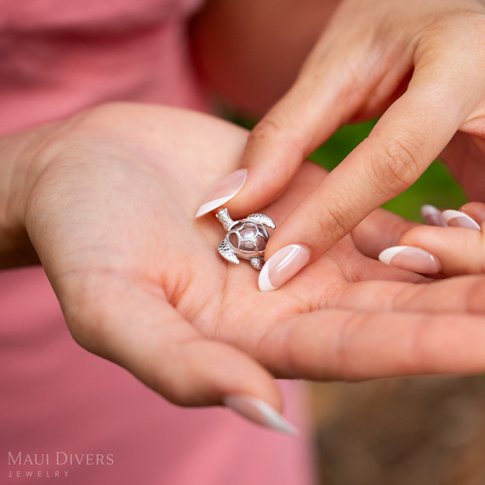 Woman closing a Pearl Honu Pendant in Sterling Silver with a Natural Pink Freshwater Pearl inside.
