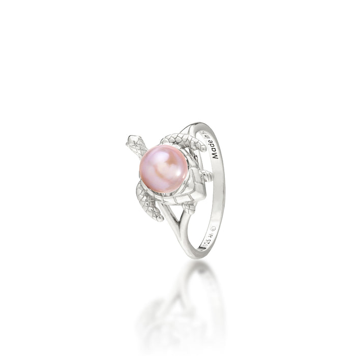 A sterling silver ring featuring a central lavender freshwater pearl set on a Hawaiian green sea turtle's back, on a white background with a soft reflection.