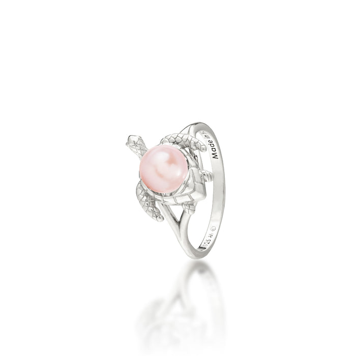 A sterling silver ring featuring a central pink freshwater pearl set on a Hawaiian green sea turtle's back, on a white background with a soft reflection.