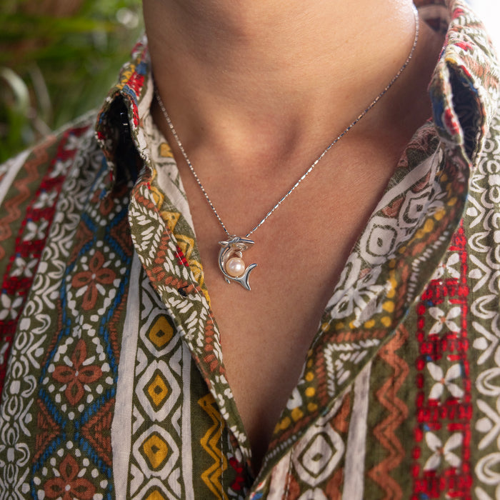 23mm Pick A Pearl Shark Pendant in Sterling Silver with a Peach Pearl on a person's neck with a colorful patter shirt
