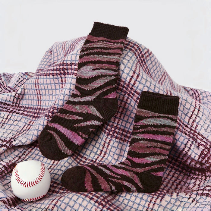 Front view of  pink camouflage socks with dark brown cuffs and toes, displayed on a plaid blanket.