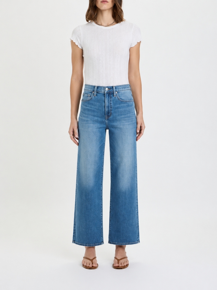Person wearing a white t-shirt and blue jeans on a white background