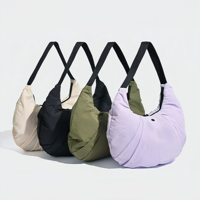 Four pleated nylon crescent shoulder bags in beige, black, olive, and light purple with black straps.
