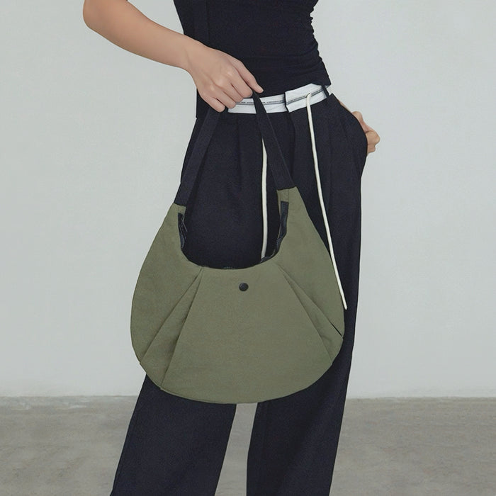 Model carrying an olive green nylon  crescent bag handheld , ideal for city walks and gifting.
