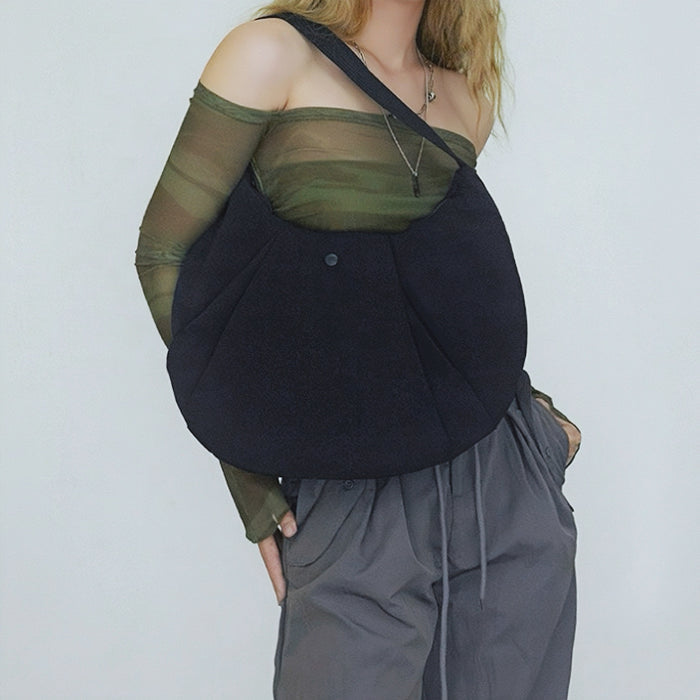 Model carrying a black nylon shoulder bag, easy for commuting and weekends.
