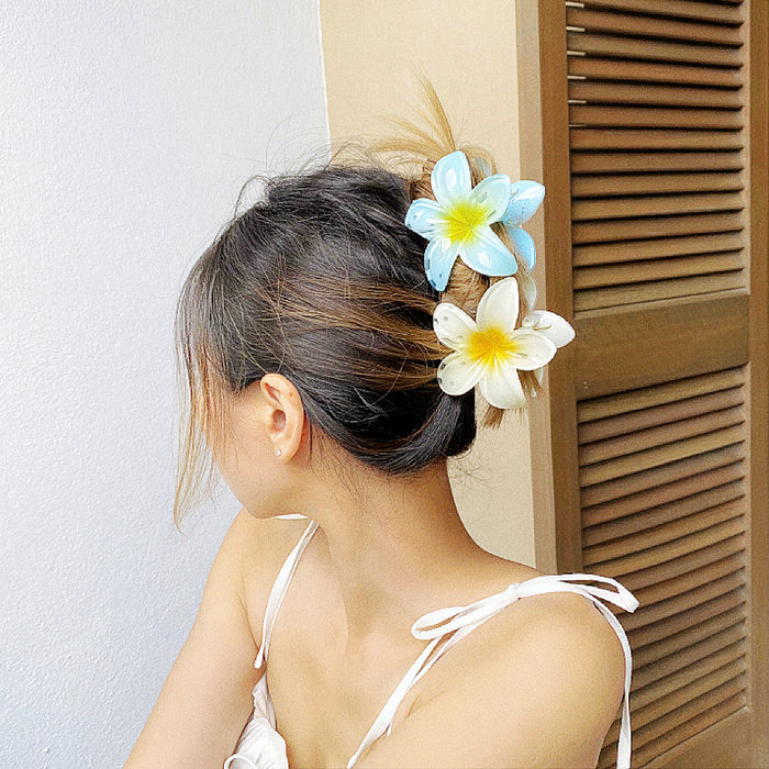 Model wearing two colors of Plumeria Hair Claws, one blue and one yellow.
