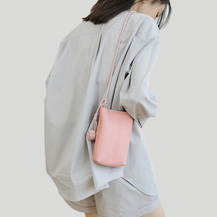 Back view of model wearing the pink leather crossbody bag, showing the slim profile.