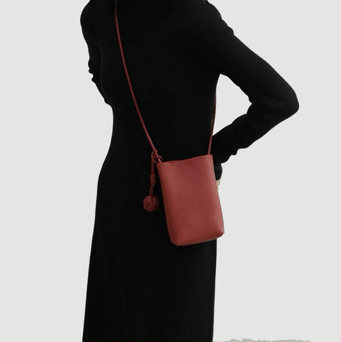 Model wearing the red leather crossbody bag against a black dress, sophisticated view