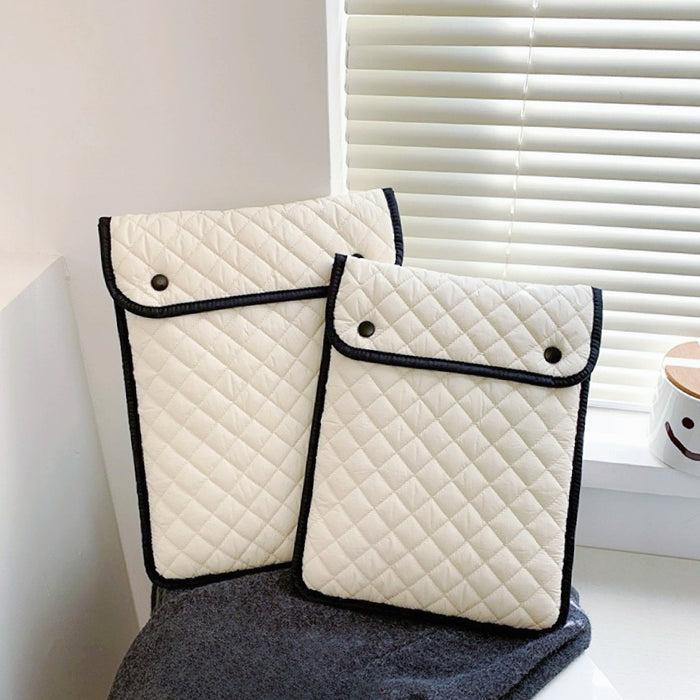 Two cream white cotton puffy diamond quilted laptop sleeves with black trim and snap closures. great for everyday carry.