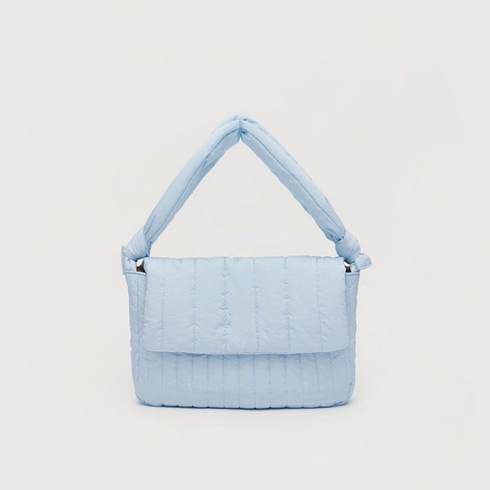 Front view of Light blue puffy quilted nylon bag with an adjustable knotted strap and magnetic flap closure.