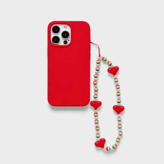 Angled view of Rainbow Heart Phone Charm  hanging on a red phone case, easy to attach to bags and phones.