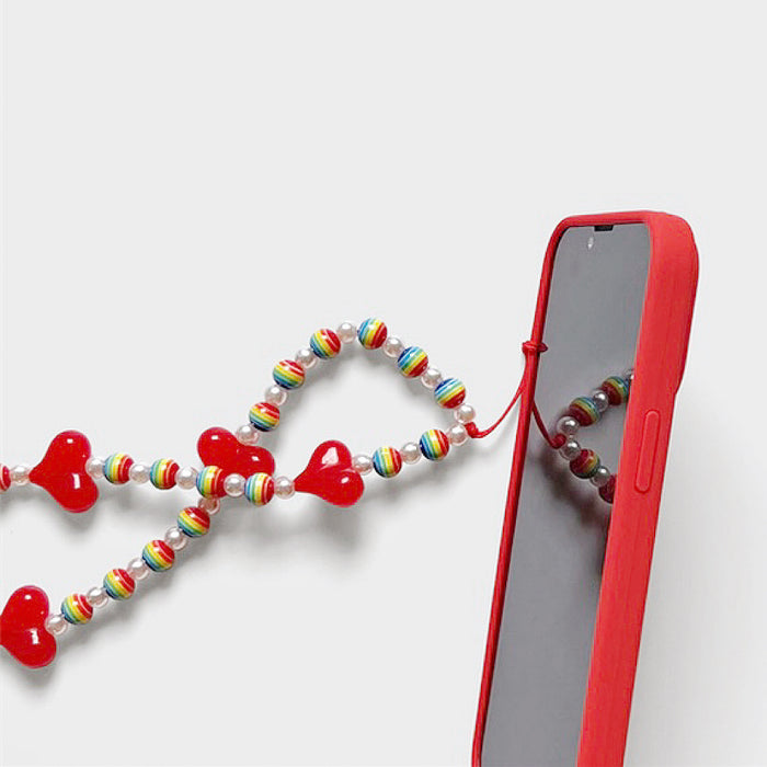 Side view of Rainbow Heart Phone Charm with a red phone case , great for everyday styling and gifting.