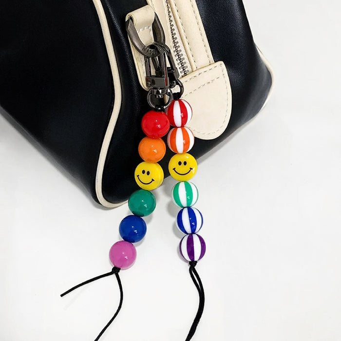 Two style of Rainbow Smile Bead Link Bag Charms hanging on a bag zipper, ideal for everyday outfits and street style.