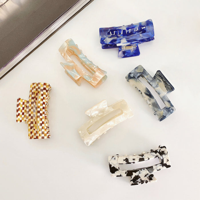 Angled view of six rectangle acrylic hair claws in various marbled colors.