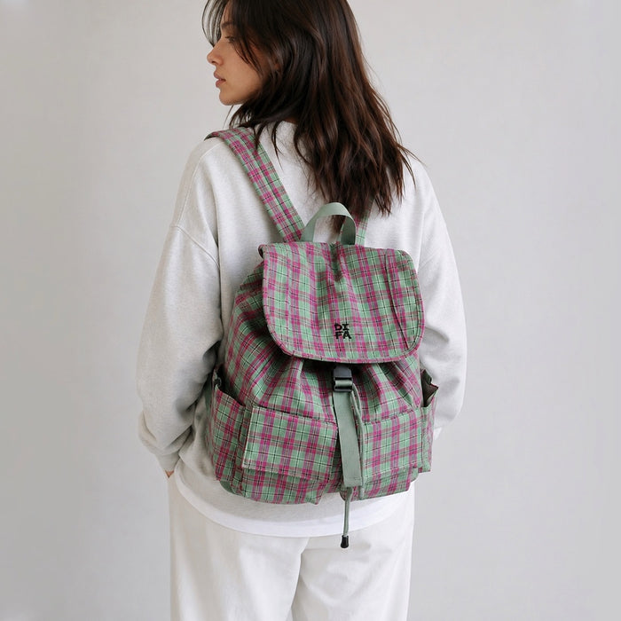 Back view of a model wearing the pink and green plaid laptop backpack flat against the lower back.