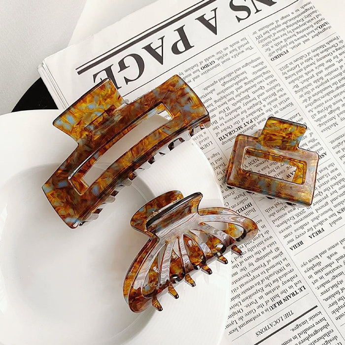 Set of three retro brown tortoiseshell acrylic hair claws in varying sizes and shapes .