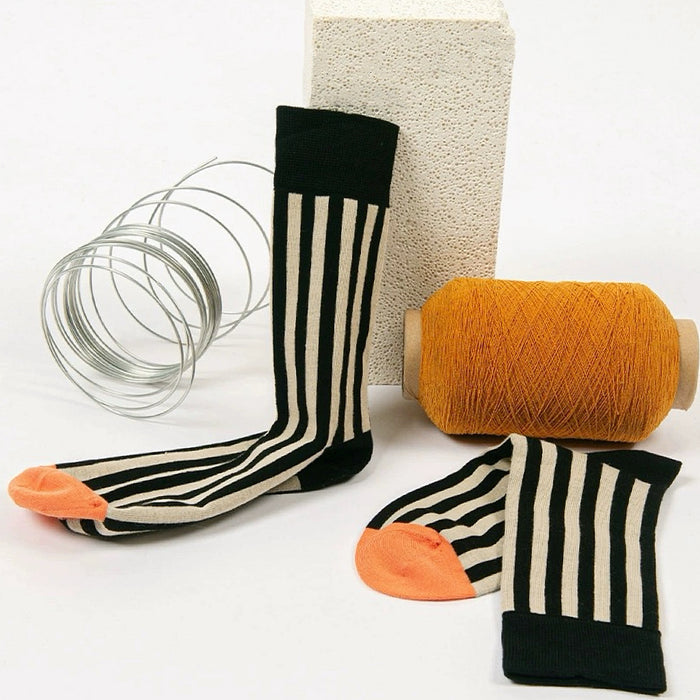Angled view of Retro stripe orange socks with black and cream vertical stripes and orange toe.
