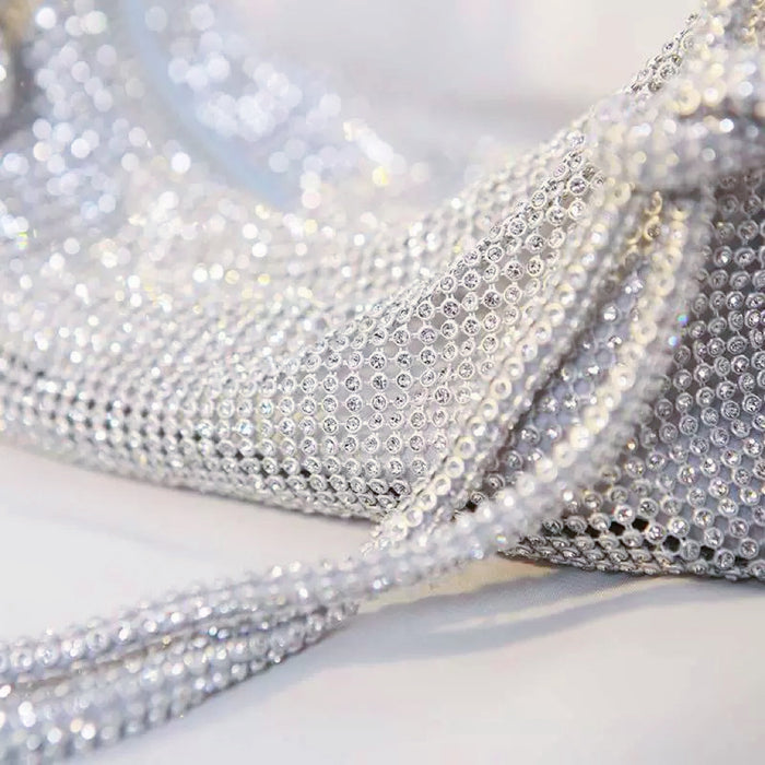 Angled view of a sparkling silver rhinestone hobo bag, showcasing its shimmering material and intricate design.